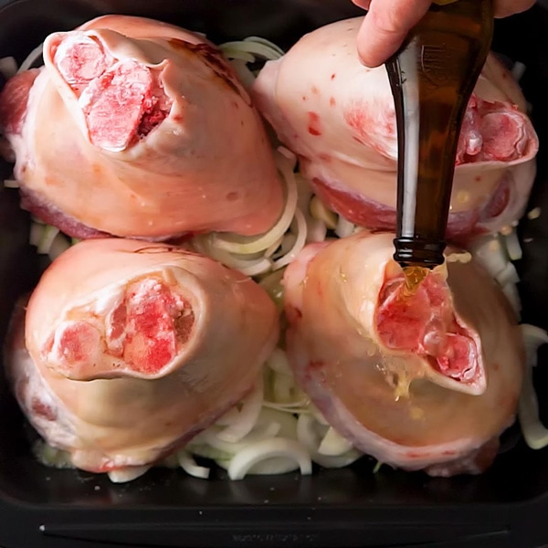 Pouring beer over the Schweinshaxe in the pan for German Roast Pork Knuckle