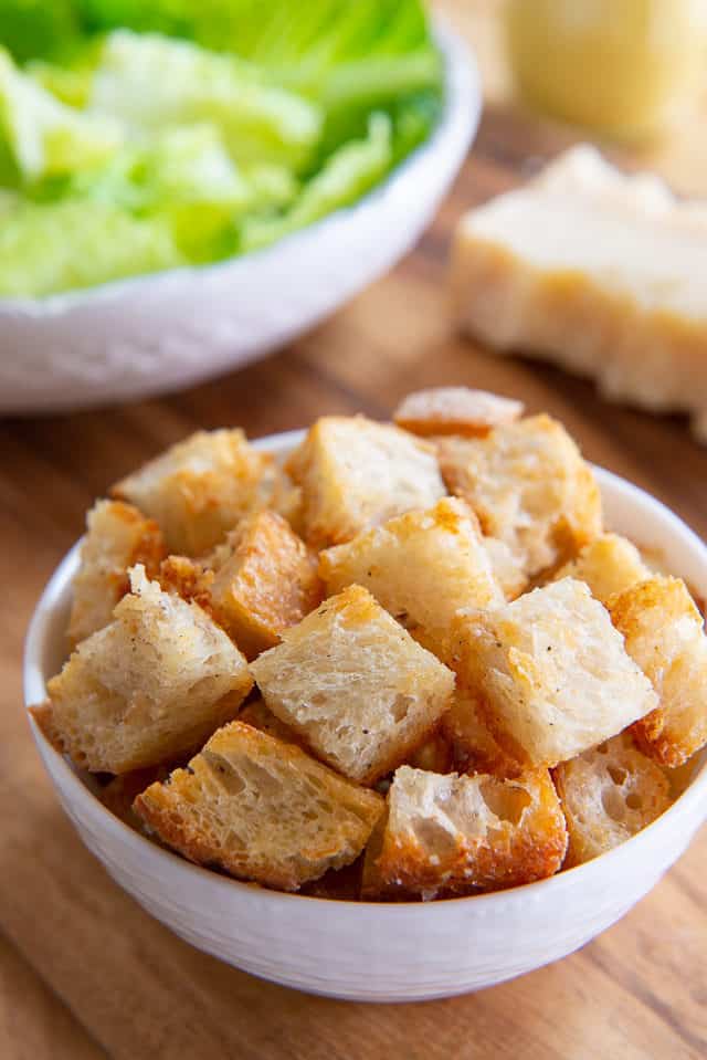 Homemade Croutons - In a White bowl on Wooden Board