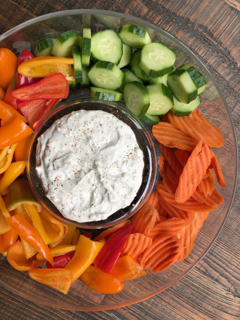 overhead shot of blue cheese dip surrounded by cucumbers, carrots and bell peppers