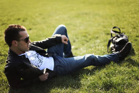 stylish guy relaxing on lawn in park